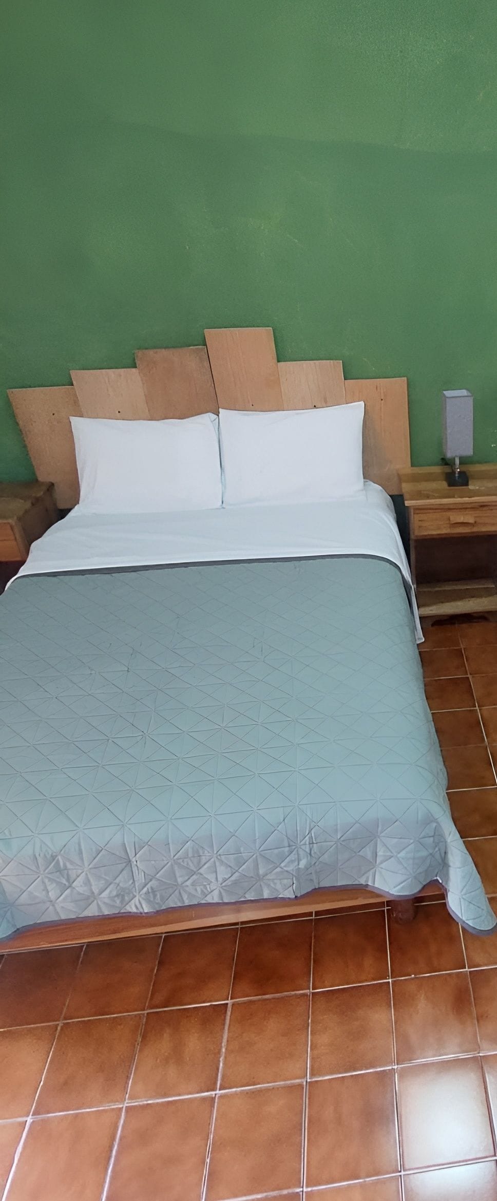 Una cama con cabecera, almohada y manta.