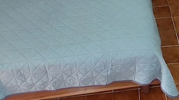 Una cama con cabecera, almohada y manta.