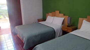 Habitación de hotel con dos camas, una pared de acento verde y suelo de baldosas.