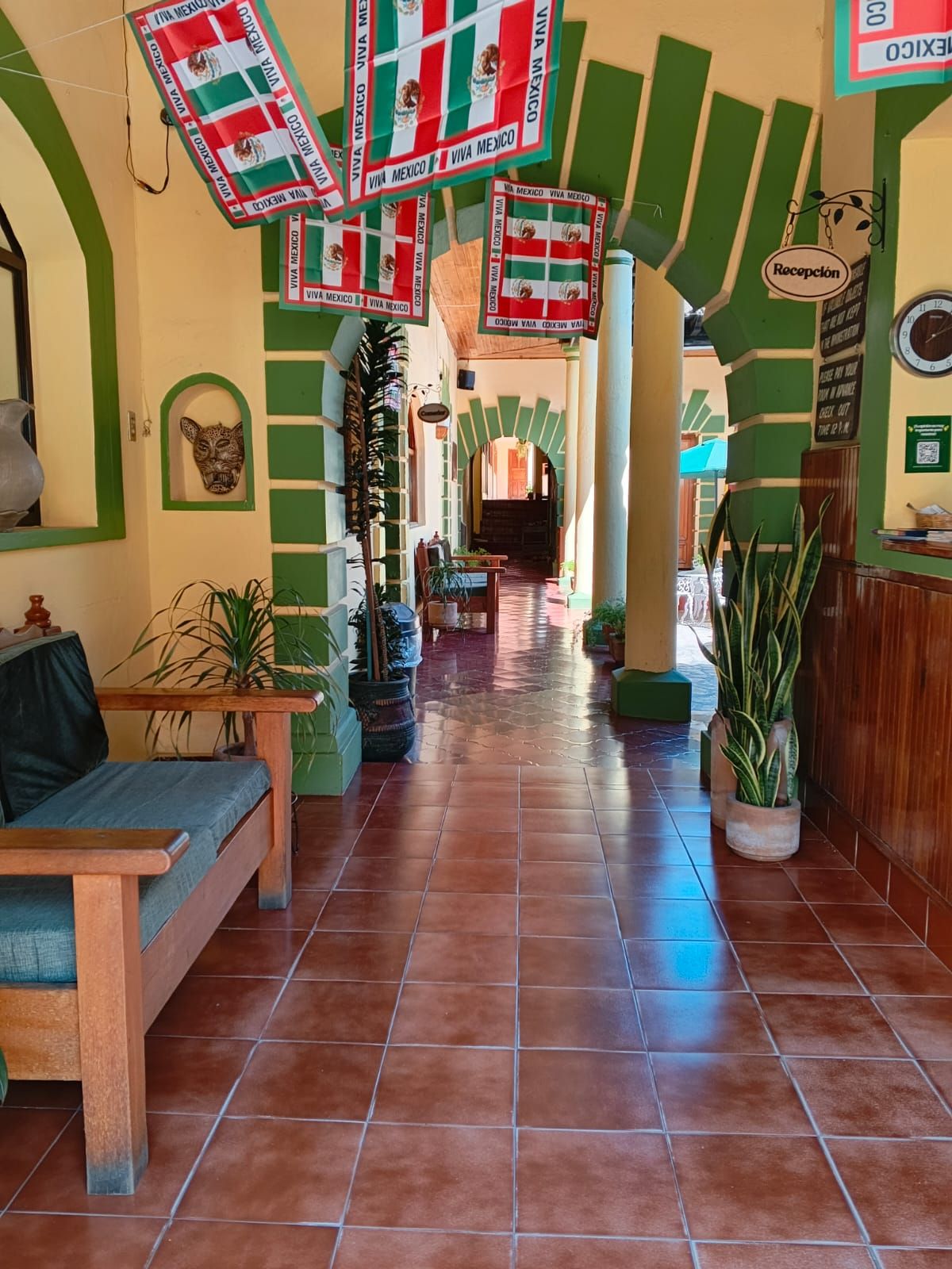 Un hall de hotel con piso de baldosas, un mostrador de recepción y un sofá.