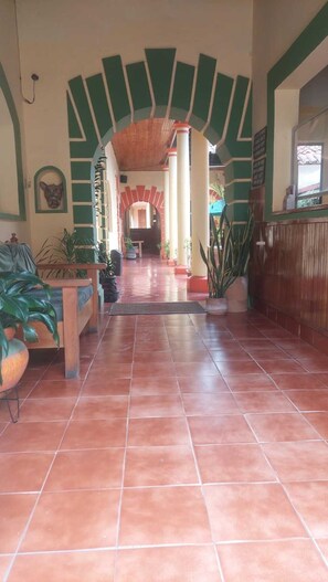 A hallway with a tiled floor, a wooden bench, and a reception desk. - San Cristóbal Bleisure Hotel (San Cristóbal de las Casas)
