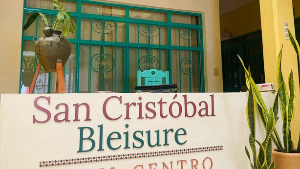 Opastekyltti, jossa lukee ”San Cristóbal Leisure Hotel Centro”, ja jossa on koristeellinen ikkuna sekä ruukuissa olevia kasveja.
