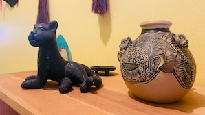A black sculpture of a cat and a decorated ceramic pot on a wooden surface. - San Cristóbal Bleisure Hotel (San Cristóbal de las Casas)