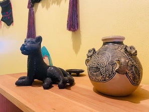 A black sculpture of a cat and a decorated ceramic pot on a wooden surface. - San Cristóbal Bleisure Hotel (San Cristóbal de las Casas)