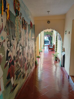 A hallway with a mural on the left, leading to a room with a car parked outside. - San Cristóbal Bleisure Hotel (San Cristóbal de las Casas)