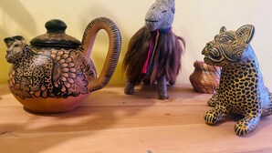 A shelf with a ceramic teapot, a small figurine of a llama, and a leopard figurine. - San Cristóbal Bleisure Hotel (San Cristóbal de las Casas)