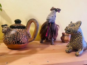 A shelf with a ceramic teapot, a small figurine of a llama, and a leopard figurine. - San Cristóbal Bleisure Hotel (San Cristóbal de las Casas)