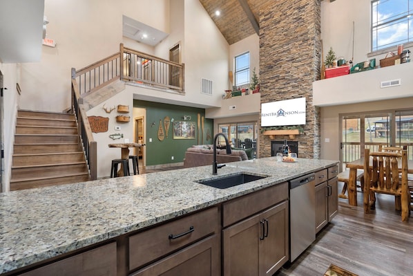 A spacious kitchen with a granite countertop, wooden cabinets, and a stone accent wall.