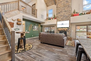 A spacious living area with a fireplace, a staircase, and a view of the outdoors.
