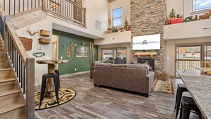 A spacious living area with a fireplace, a high ceiling, and a stone accent wall. - Near Thunder Ridge: Water View, Community Indoor Pool & Free Local Attraction Tickets (Hollister)