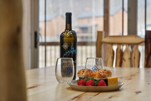 A dining table with a plate of food, a bottle of wine, and two glasses.