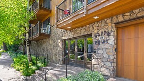 A stone building with a wooden balcony, a garage door, and a sign with the number 205. - Southpoint 2D | Prime Access to Aspen Mountain, 2 BED / 2 BATH with Stunning Mountain Views (Aspen)