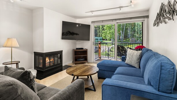 A modern living room with a fireplace, a blue sofa, and a flat-screen TV. - Southpoint 2D | Prime Access to Aspen Mountain, 2 BED / 2 BATH with Stunning Mountain Views (Aspen)