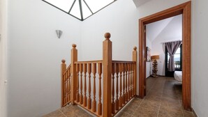 Een trap met houten spijlen die leidt naar een slaapkamer met een bed en een raam.