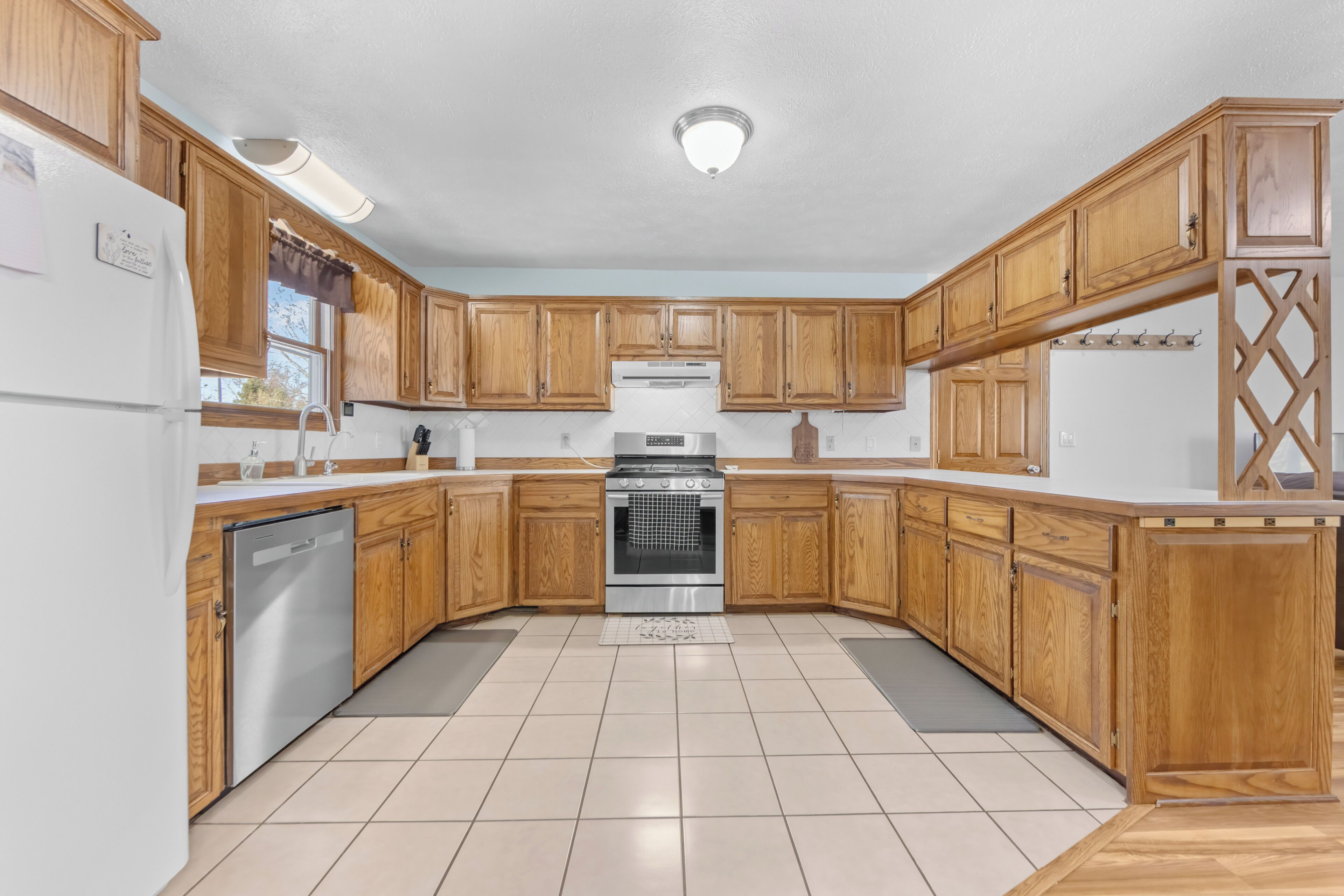 A kitchen with wooden cabinets, a stainless steel refrigerator, and a built-in oven.