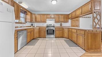 A kitchen with wooden cabinets, a stainless steel refrigerator, and a built-in oven.