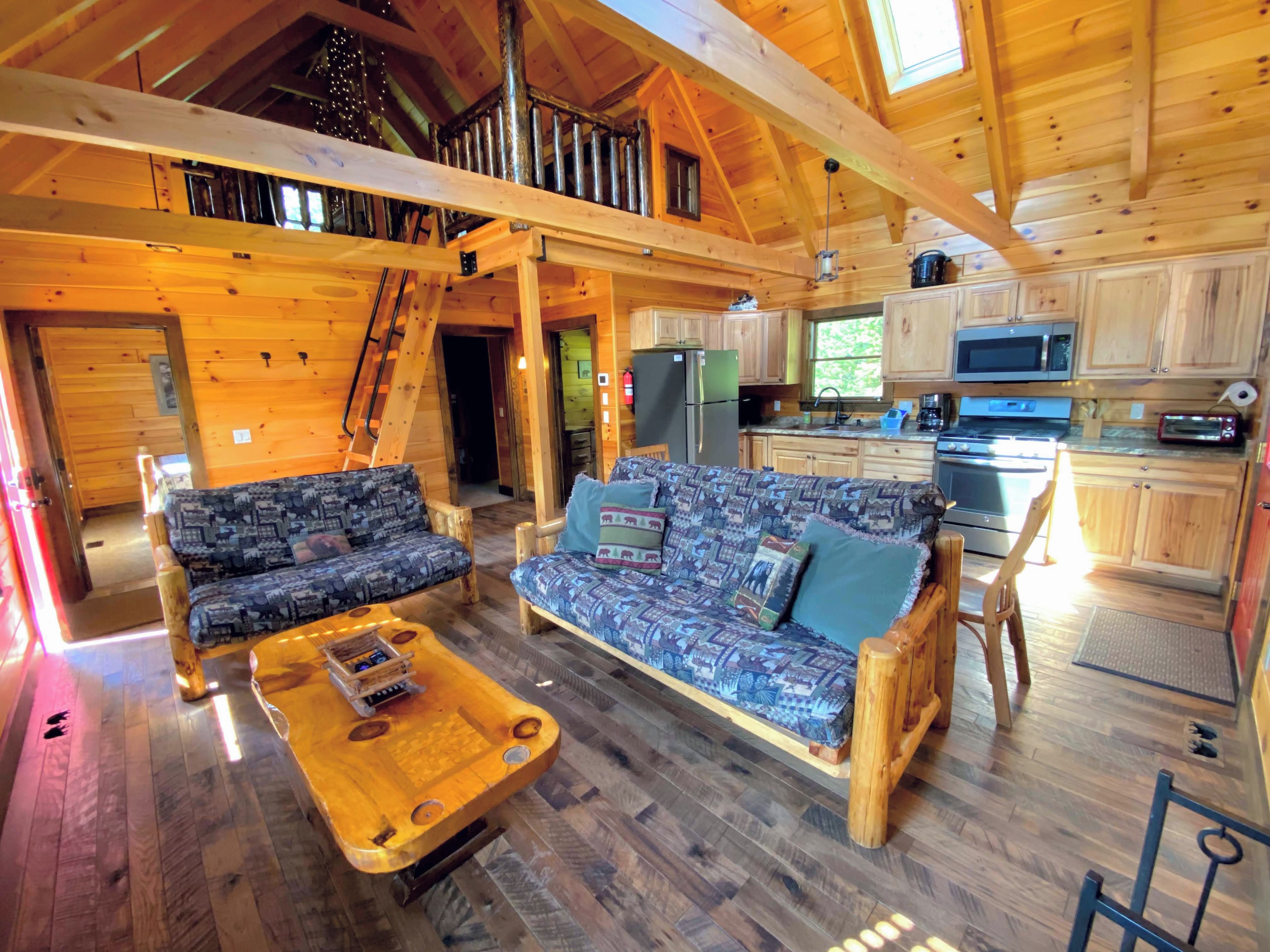 Ein Holzblockhaus-Innenraum mit einer Sofaecke, einem Esstisch und einer Küchenzeile.