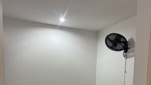 A small, clean room with two beds, a nightstand, a wall-mounted fan, and a door. - Furnished apartment, Excellent location, free parking (Cereté)