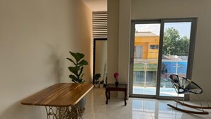 A modern living room with a wooden table, a rocking chair, and a view of a swimming pool through a glass door. - Furnished apartment, Excellent location, free parking (Cereté)