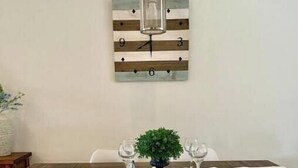 A dining area with a wooden table, white chairs, and a hanging light fixture. - Short term rental. Home away from your home. (Celina)