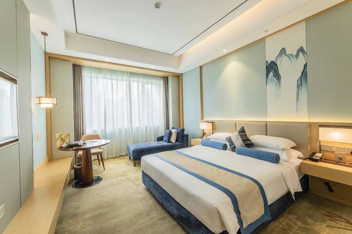 Habitación de hotel con una cama grande, un escritorio, una silla y un cuadro en la pared.