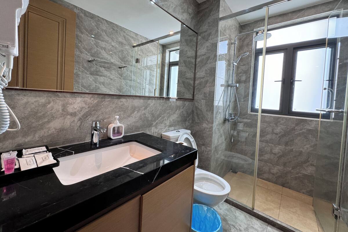 A modern bathroom with a black countertop, a glass shower enclosure, and a toilet.