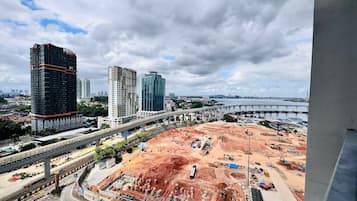 A construction site with multiple high-rise buildings in the background, a bridge, and a highway.