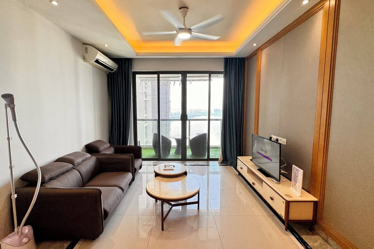 A modern living room with a sofa, a coffee table, a TV, and a ceiling fan.