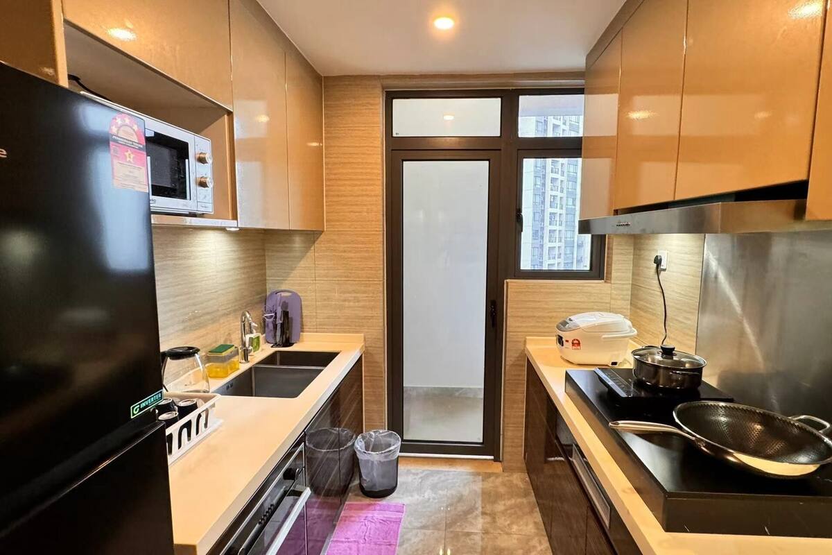 A compact kitchen with a refrigerator, microwave, stove, and sink.