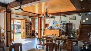A spacious dining area with wooden furniture and a chandelier.