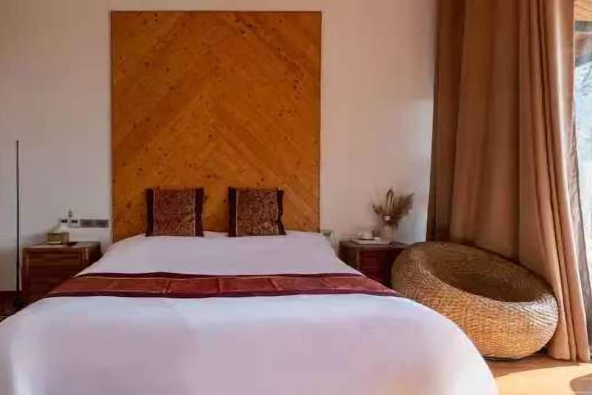 Ein Schlafzimmer mit einem großen Bett, einem Holz-Kopfteil und Blick ins Freie.