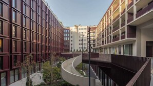 Um edifício moderno com uma escadaria curva e um pátio com vegetação.