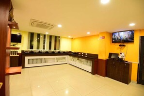 Un hall de hotel con una barra de buffet, un televisor y un cartel con la palabra 'NO' en la pared.