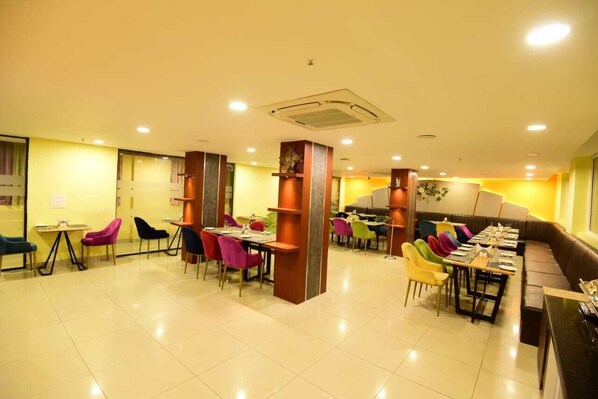 A restaurant with multiple dining areas, each with tables and chairs. There are colorful chairs and a variety of table settings.