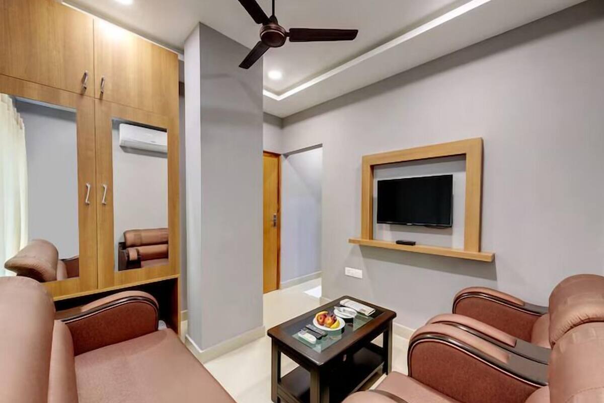 A modern living room with a sofa, a coffee table, a TV mounted on the wall, and a ceiling fan.