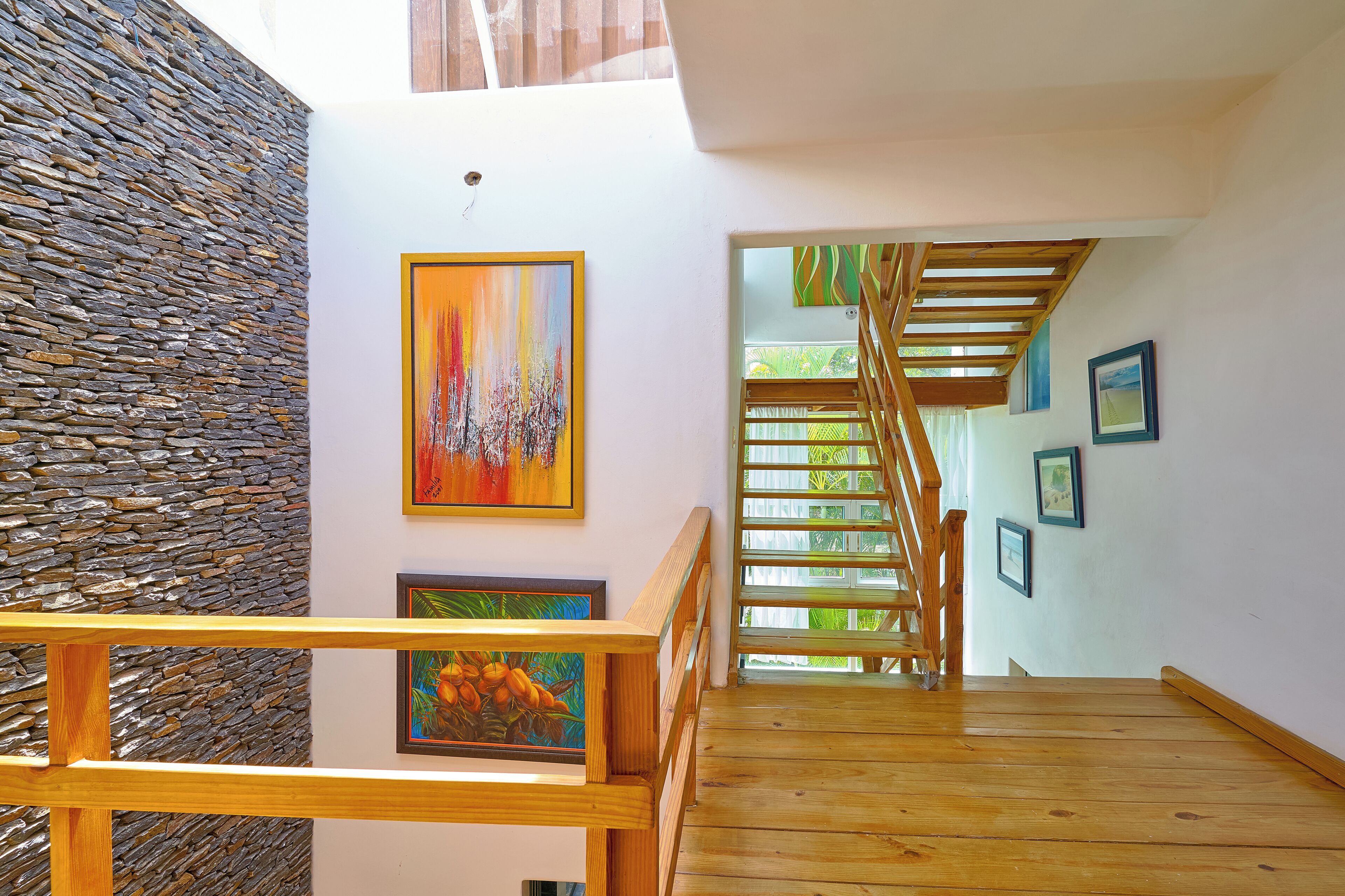 A wooden staircase with a stone wall and artwork on the walls.