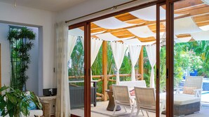 Habitació àmplia amb una porta corredissa de vidre que dona a una zona exterior amb piscina i ombrelles.