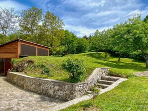 Escape to a serene cabin nestled among lush greenery on a grassy hill.