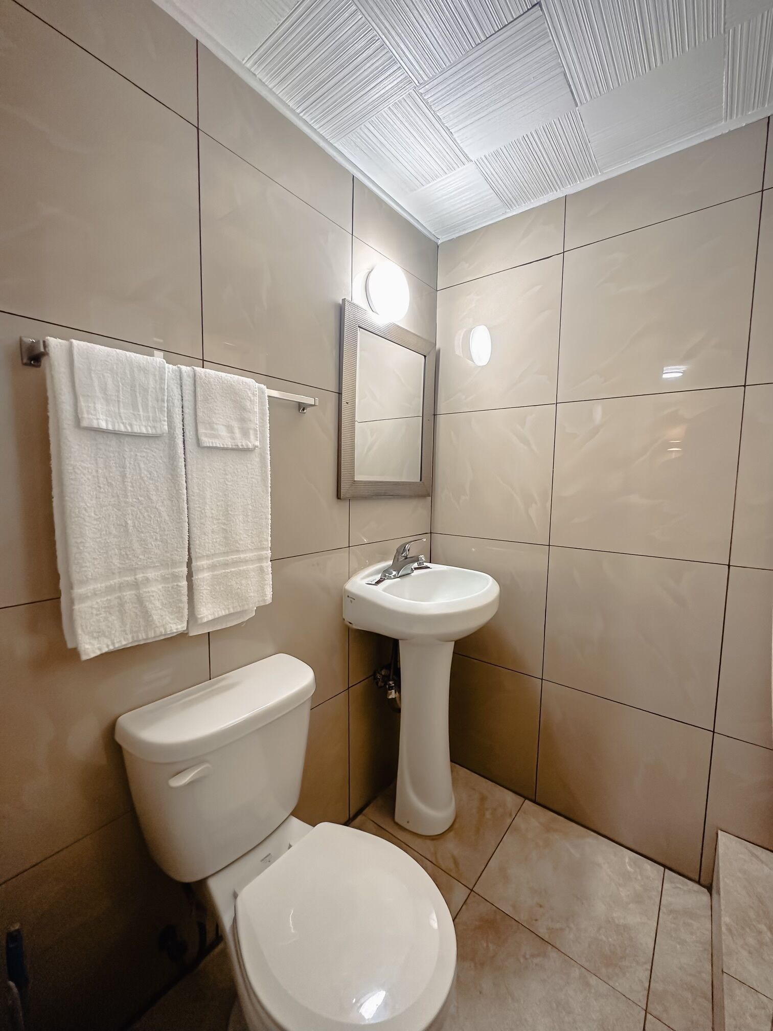A bathroom with a toilet, sink, and mirror.