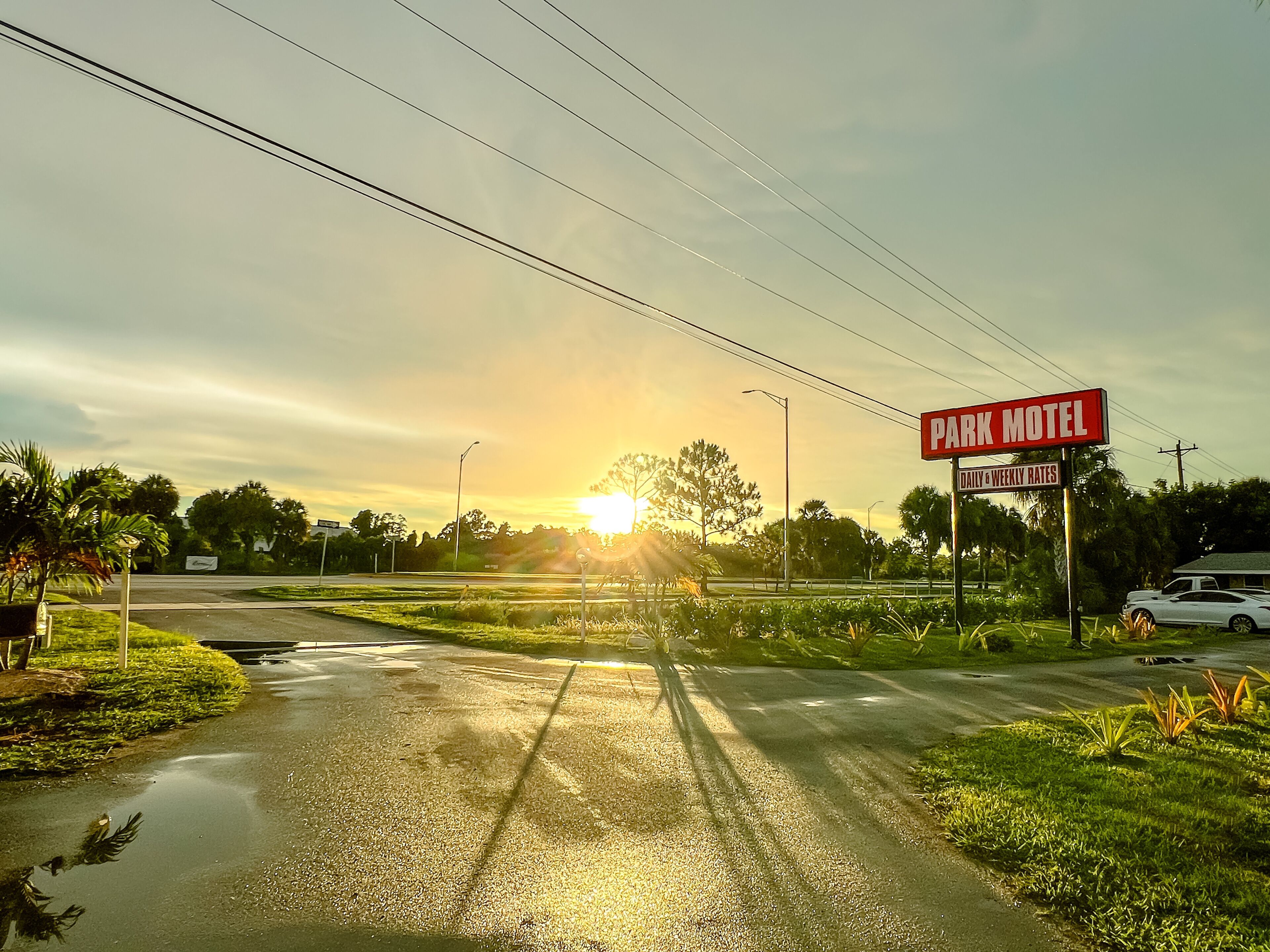Een weg die naar een motel aan een park leidt, met een bord waarop dag- en weektarieven staan.