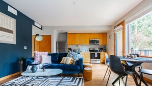 A modern living room with a blue sofa, a round coffee table, and a patterned rug. - Sophari East: Bellevue Apartments (Bellevue)