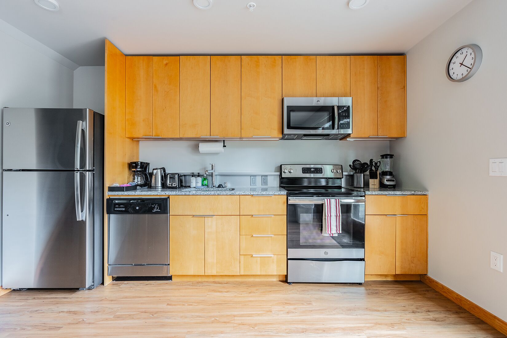 Una cucina moderna con mobili in legno, elettrodomestici in acciaio inossidabile e un forno a microonde.