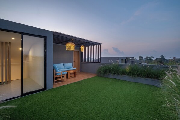 Un patio moderno al aire libre con un sofá azul, una mesa de madera y dos lámparas de mimbre.