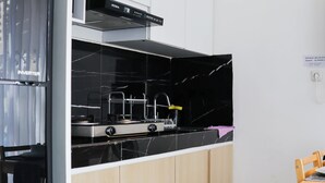 A modern kitchen with black marble countertops, stainless steel appliances, and wooden cabinets. - Otia Villa by Premier Hospitality Asia (Nusa Dua)