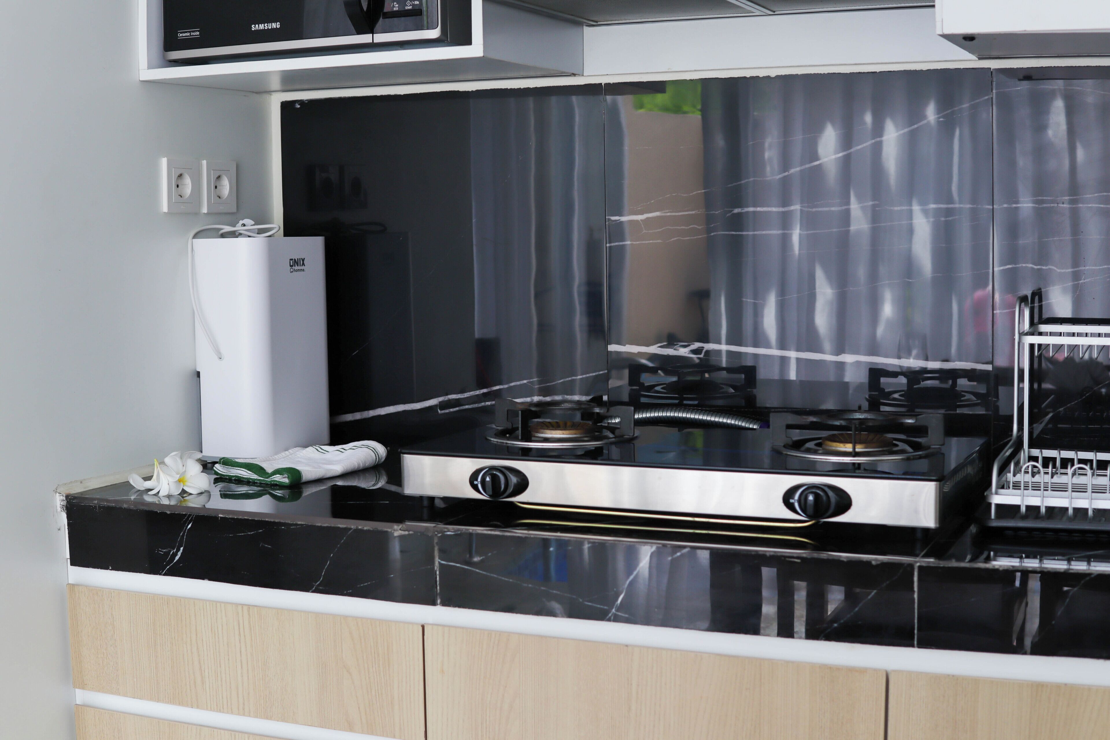 A kitchen with a black countertop, a white refrigerator, and a stove with two burners.