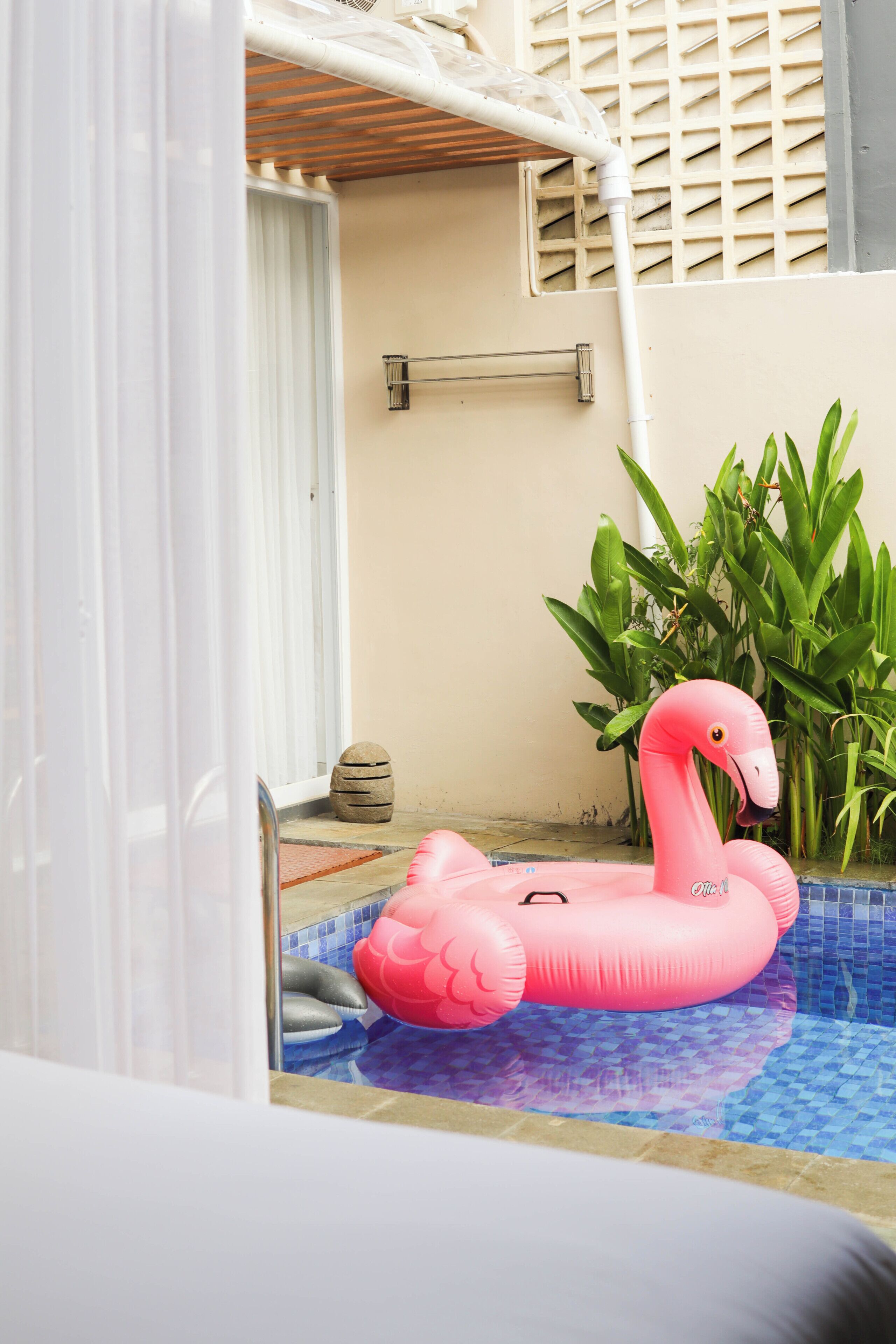 A swimming pool with a pink flamingo float.