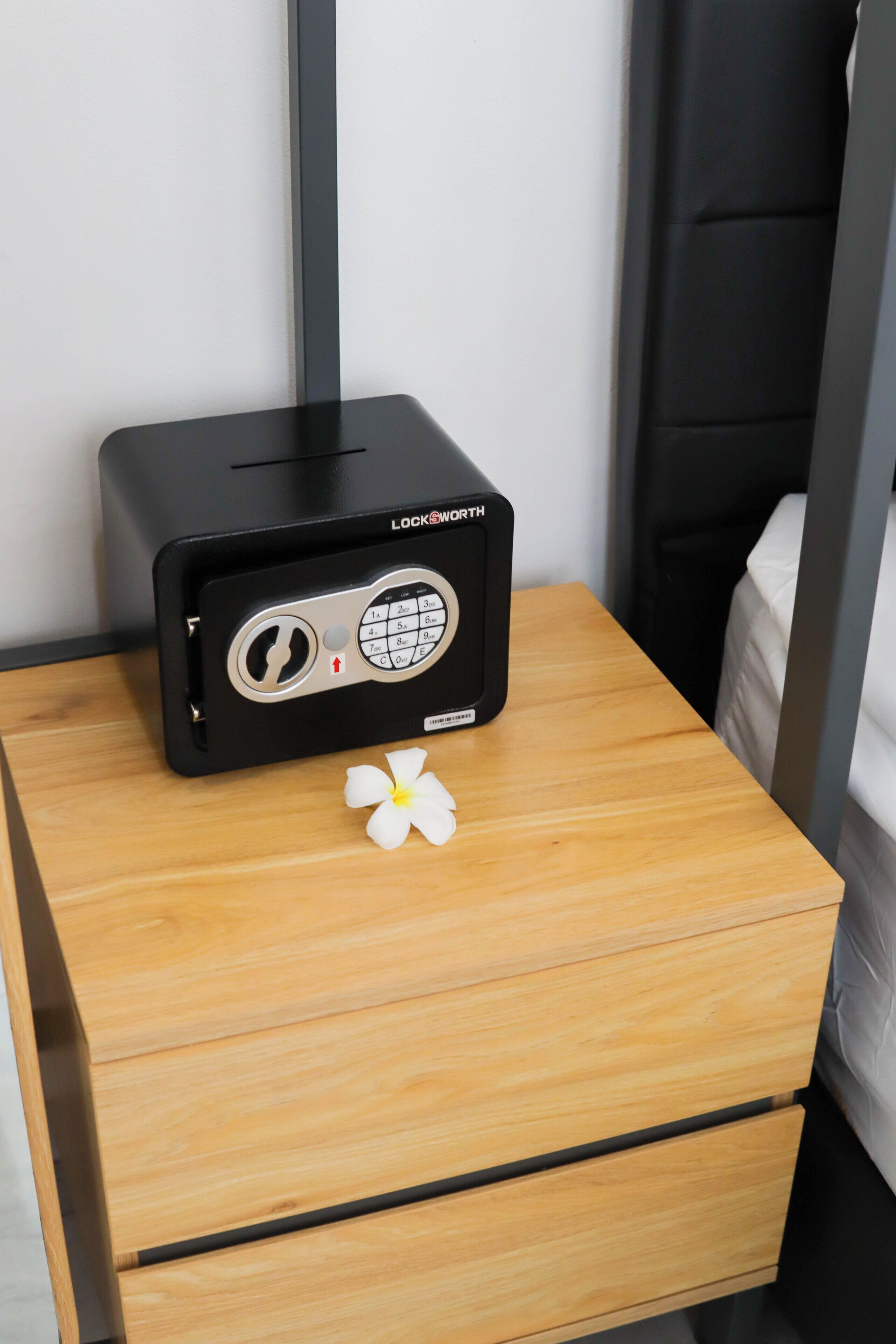 Una radio negra sobre una mesita de noche de madera con una flor blanca.