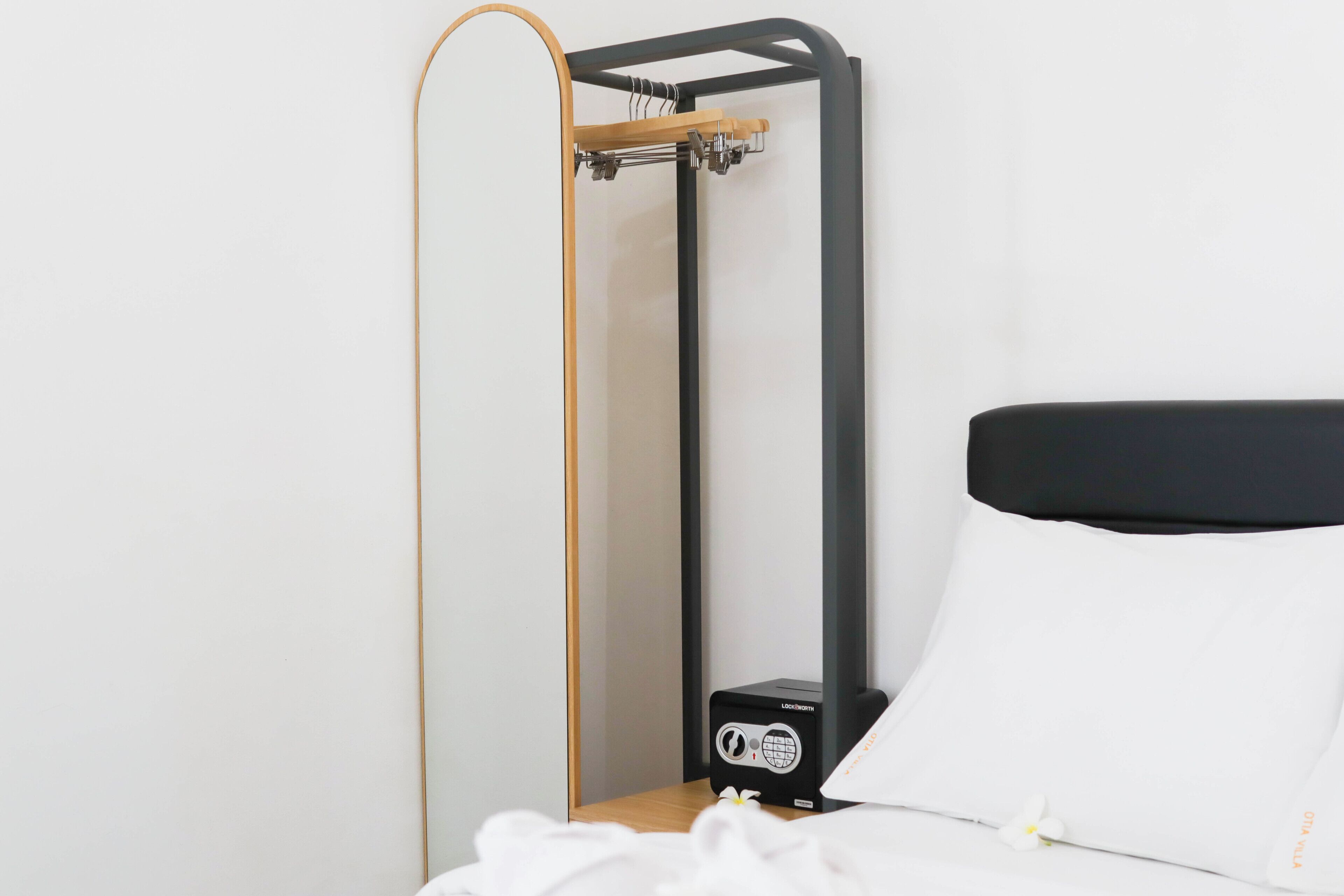 A bed with a black headboard, a wooden frame, and a small black device on the nightstand.