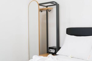 A bed with a black headboard, a wooden frame, and a small black device on the nightstand.