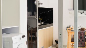 A modern kitchen with white cabinets, a built-in oven, and a dining area with a table and chairs. - Otia Villa by Premier Hospitality Asia (Nusa Dua)
